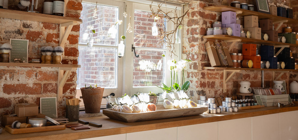 Love to b shop interior with exposed brick walls, wooden shelves filled with jars, boxes, and packaged goods, and a wooden counter holding a tray of natural soaps