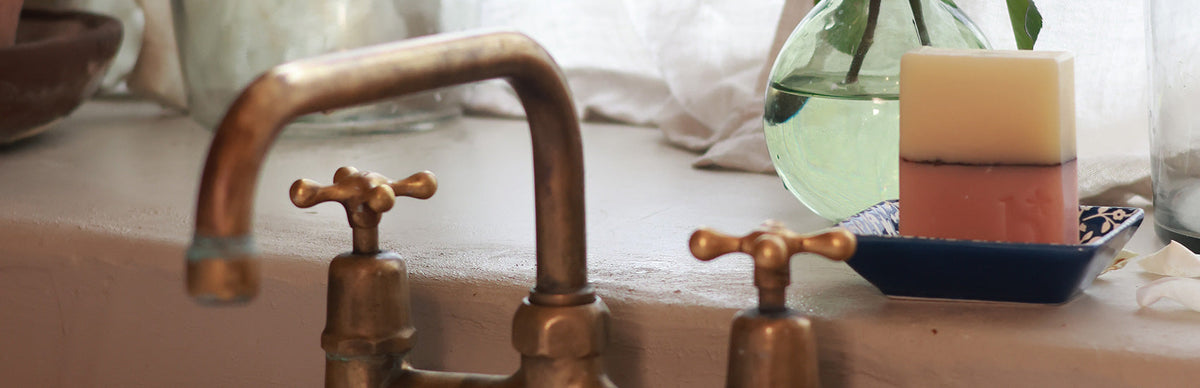 Natural hand soap bar in the kitchen next to a tap and sink sitting in a soap dish by a window