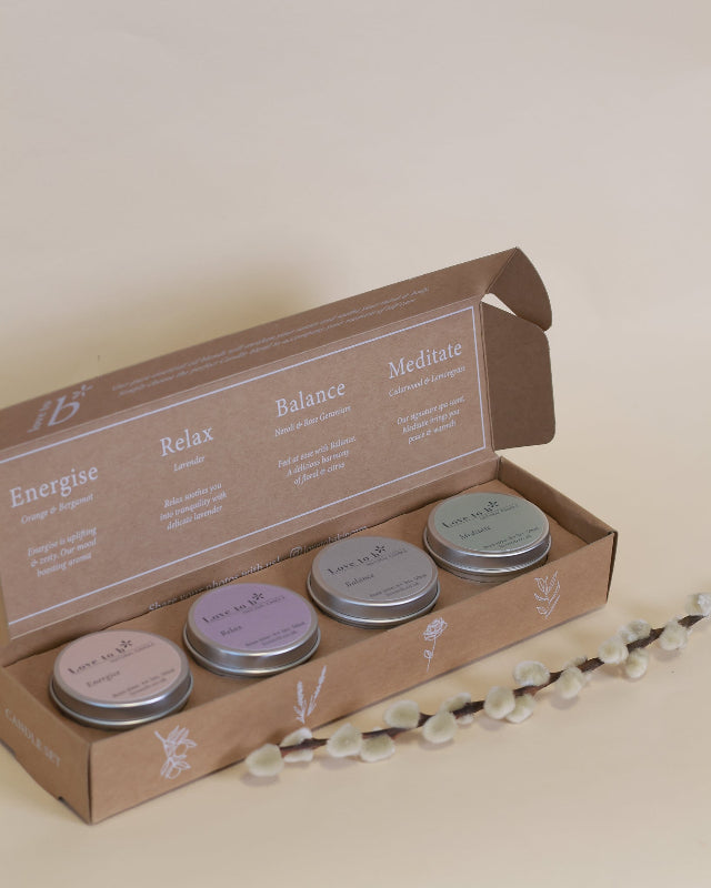 Love to b natural soy candle gift set: four small candles in metal tins, scented Energise, Relax, Balance and Meditate, in a kraft box on a beige background.