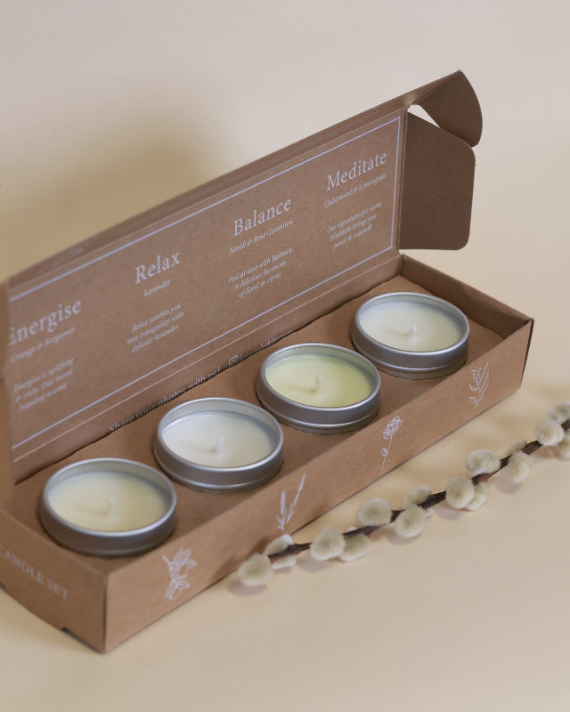 A natural candle gift set in a kraft box with four candle tins all without there lids on.