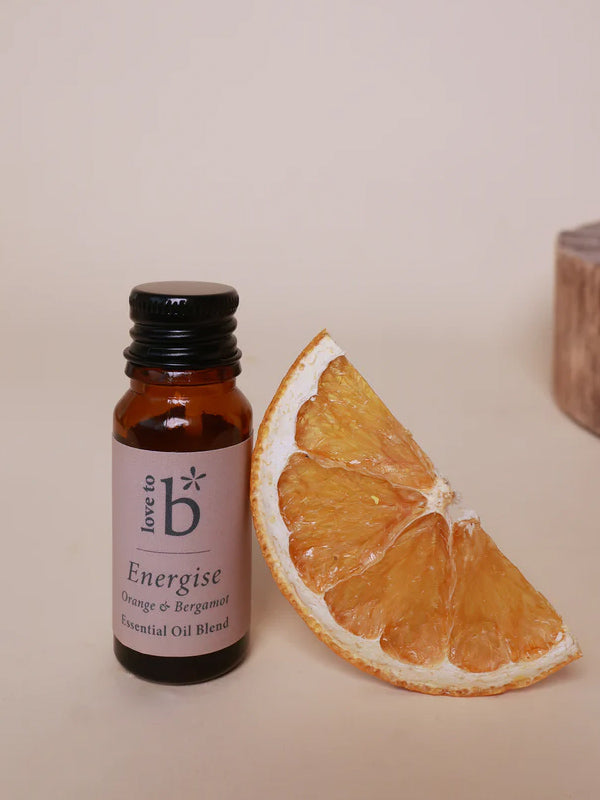 A small amber glass bottle of essential oil blend with a black cap and a pink label reading &