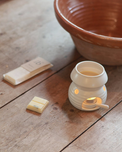 Natural soy wax bars on a wooden table with a Love to b packet in the background. A white wax burner sits to the right.