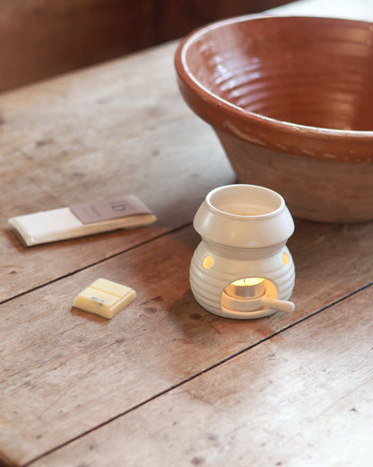 Natural soy wax bars out of the packet next to a wax burner and in front of a Love to b pack on a wooden surface.